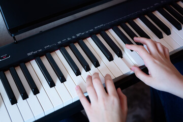 Hands of girl playing piano, selective focus. Musical instrument grand piano with woman performer.