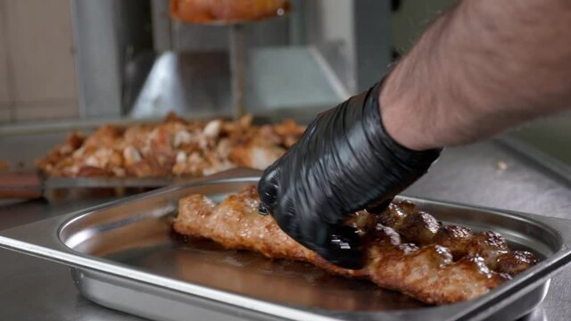 Ready to eat juicy lula kebab takes off from skewer and puts on steel tray in fast food restaurant, close-up