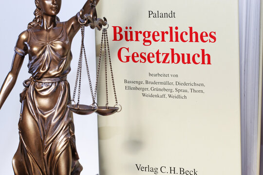 Symbolbild Gerichtsurteil: Justitia mit dem Palandt (Bürgerliches Gesetzbuch) im Hintergrund