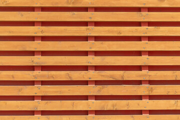 The horizontal planks are wooden. background. Sunny autumn day. Front view.
