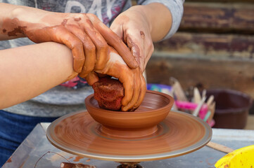 Pottery training. Female hands in clay over a potter's wheel. Young girls learn to potter