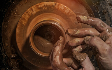 A potter makes a pot on a circle. The hands of the master create from clay. Top view