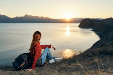 woman sits on the ground in nature in the mountains near the sea adventure sunset