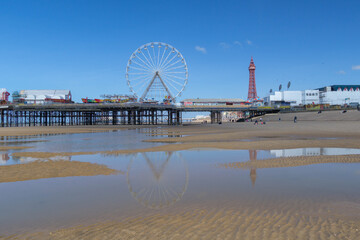 Blackpool's seaside attractions reflected on the beach at low tide on clear spring day