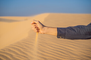 Desert, sand puffs through the fingers of a mans hand