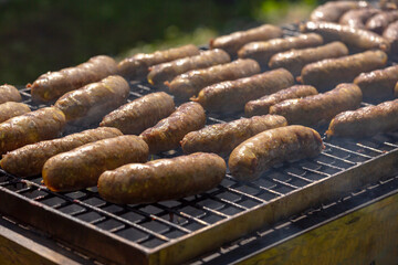 Fried Sausages. Delicious sausages sizzle over the coals on the barbecue grill. Frying sausages on the grill, close-up.