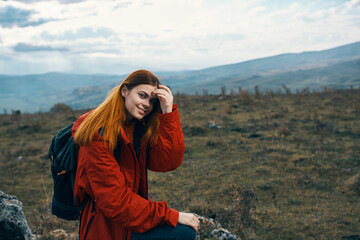 happy woman tourist sat down to rest on a meadow in the mountains in nature