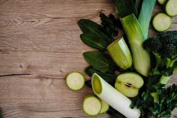 Green vegetables and fruits on a wooden background.