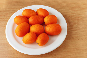 Fresh ripe kumquats on a white plate