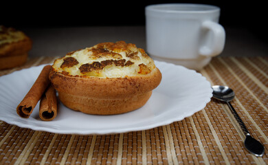 Muffin with cottage cheese and cinnamon on a white plate. Cinnamon sticks. . Muffin close up.