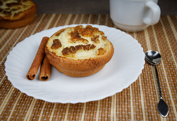 Muffin with cottage cheese and cinnamon on a white plate. Cinnamon sticks. . Muffin close up.