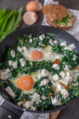 Green shakshuka. Fried eggs with wild garlic and feta cheese
