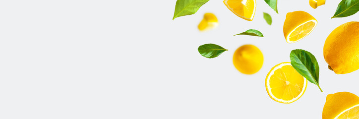 Juicy ripe flying lemons, green leaves on light gray background. Creative food concept. Tropical...