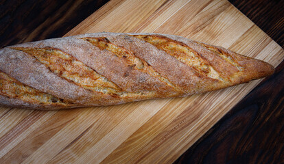 Baguette bun on a wooden cutting board.