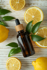 Dropper bottle with oil and lemons on white wooden table