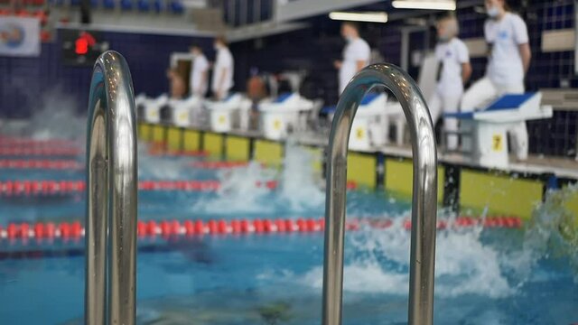 swimmers boys teenagers start jumping into the water. Swimming sports tournament. Slow motion