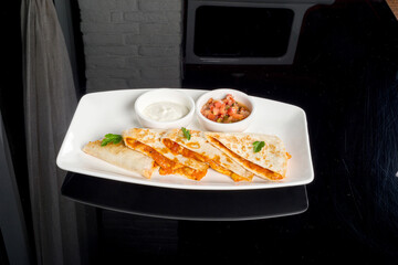 Quesadilla with sauce on a white plate filmed with reflection