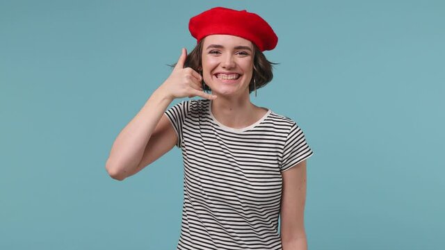 Charming Short Hairdo European Woman 20s Wear Red French Beret Hat Striped T-shirt Point Finger Camera On You Doing Phone Gesture Like Says Call Me Back Isolated On Pastel Blue Color Background Studio