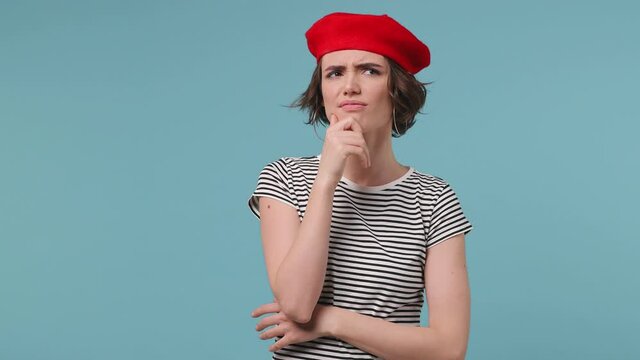 Fun confused shy shamed short hairdo young woman 20s wear red french beret hat striped t-shirt look camera spread hands say oops ouch oh i am so sorry isolated on pastel blue color background studio