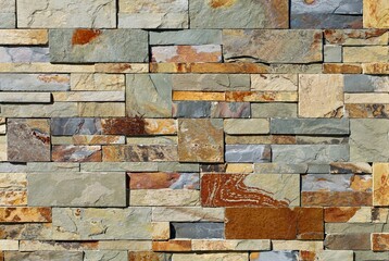 Stone cladding wall made of  stacked slabs of natural multicolor rocks. Panels for exterior, background and texture.