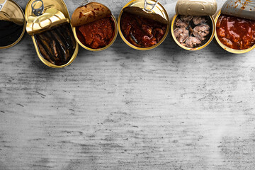 Top view of opened cans with fish conserves on wooden background