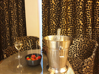 A glass of champagne with strawberries on the table in the leopard print hotel room.