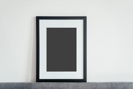 Blank wooden photo frame stands in the interior on a white background. Mockup poster frame.