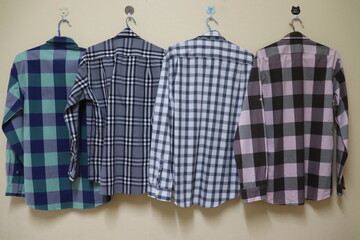 A fashionable long-sleeved shirt with a green, black and pink plaid pattern was ironed smooth and hanging  a yellow wall. Ideas for a modern fairytale outfit It is popular with teen for travel.