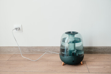 Modern air humidifier on a white wall background. Humidifier spreading steam into the living room