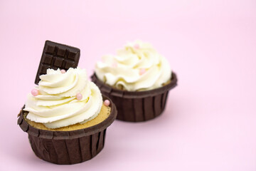  Set  cupcakes with vanilla cream decorated with  pink beads  and chocolate on pink background with  copy space for text .