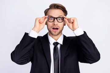 Photo of young handsome man amazed shocked surprised hands touch glasses isolated over grey color...