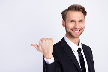 Photo of young man happy positive smile indicate thumb empty space suggest sale advert isolated over grey color background