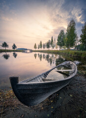 Old rowboat with calm lake and mood sunset at autumn evening in Finland - 426586525