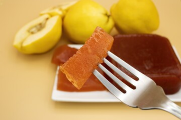 Selective focus on a delicious homemade quince jam, homemade quince flesh, on a creamy background, with quinces out of focus in the background
