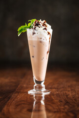Chocolate milkshake cocktail on the wooden table with reflection