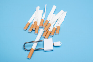 Quit smoking concept. Cigarettes squeezed into a lock on a blue background. Bad limiting habit.