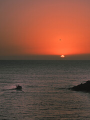 Fototapeta premium Atardecer desde la playa con barca yendo al horizonte