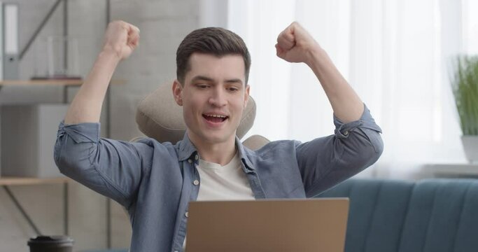 Satisfied Man Freelancer Reading e - mail Message with Great News on Laptop. Attractive Smiling Man got a new Programming Payable Project sitting at Office Room. Victory Concept. Opportunity.