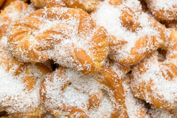 Sweet pretzels in a bunch. The pretzels are sprinkled with white coconut chips.