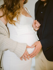 Close up of a couple holding their hands on pregnancy belly