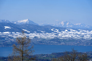 Panoramic landscape with lake Zurich and snow capped Swiss alps in the background. Photo taken April 8th, 2021, Zurich, Switzerland.