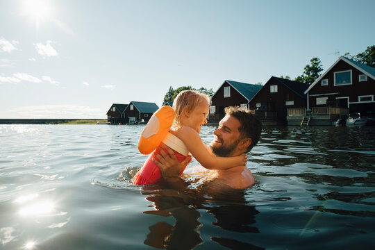 Side view of cheerful daughter with father in lake during vacations