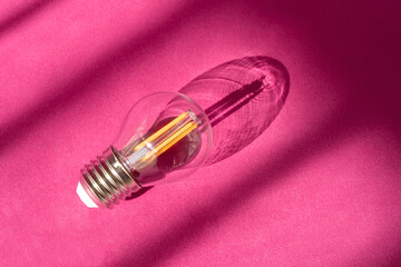 Light bulb on purple background with shadows close up. Lightbulb on surface. Creative new idea, innovation, inspiration concept. Top view