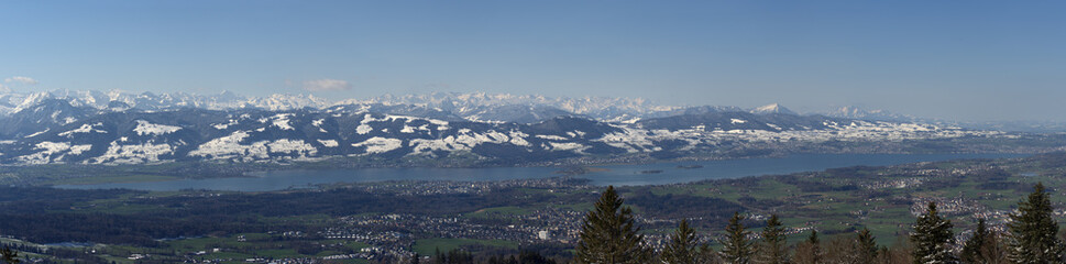 Panorama view of upper lake Zurich with snow capped mountains in the background. Photo taken April 8th, 2021, Bachtel, Switzerland.