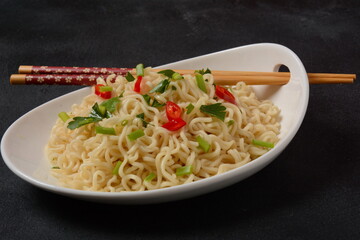 Bowl of instant noodles with chopsticks on black background.