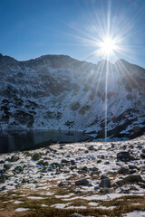 Sunny day in Tatra National Park, Poland. The lake is in the shadow, fresh snow is covering the valley. Selective focus on the mountain ridge, blurred background.