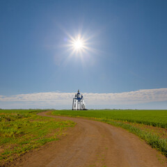 Fototapeta na wymiar christian church among green rural fields under a sparkle sun