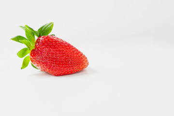 One red strawberry with green leaves on white background