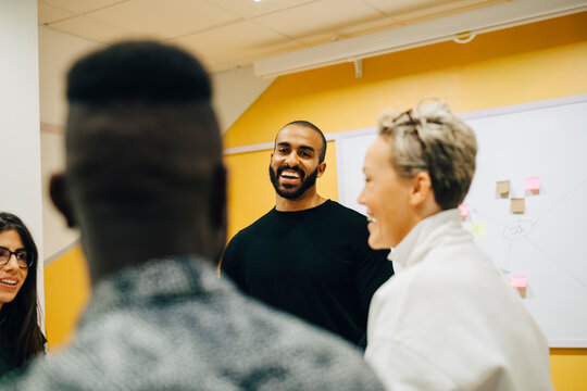 Smiling business people discussing during meeting at office