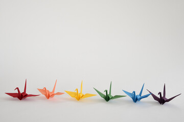 LGBT rainbow-colored Origami paper cranes on white background.